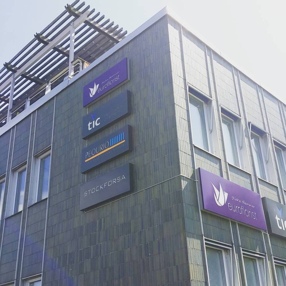 A modern office building facade with signage for Euroflorist, TIC and other companies.
