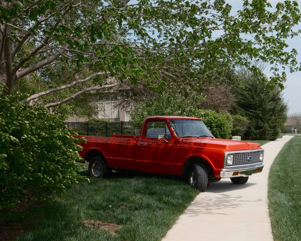 Red truck parked across the sidewalk in a suburban neighborhood