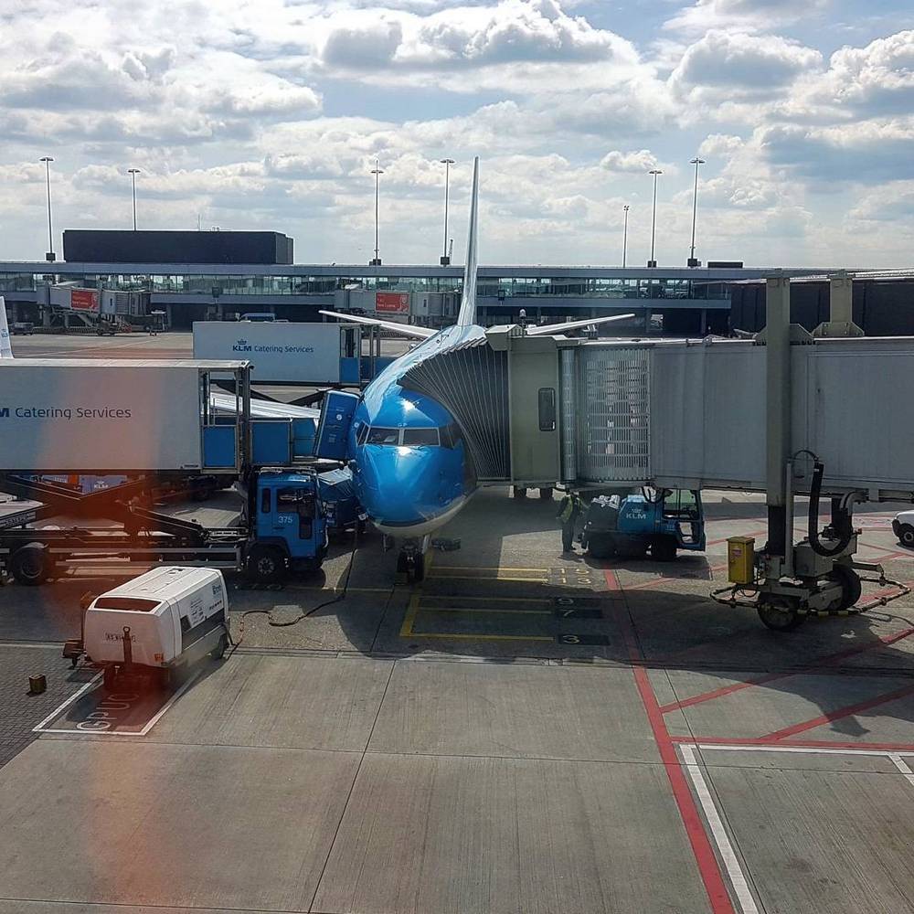 A KLM airplane parked at an airport gate with a jet bridge attached.