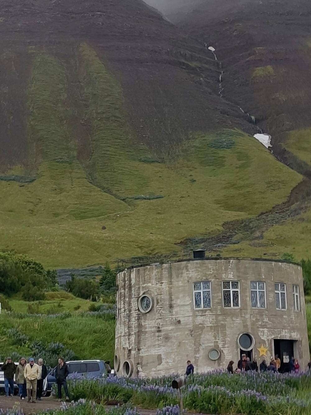 Circular concrete building in front of a treeless mountain