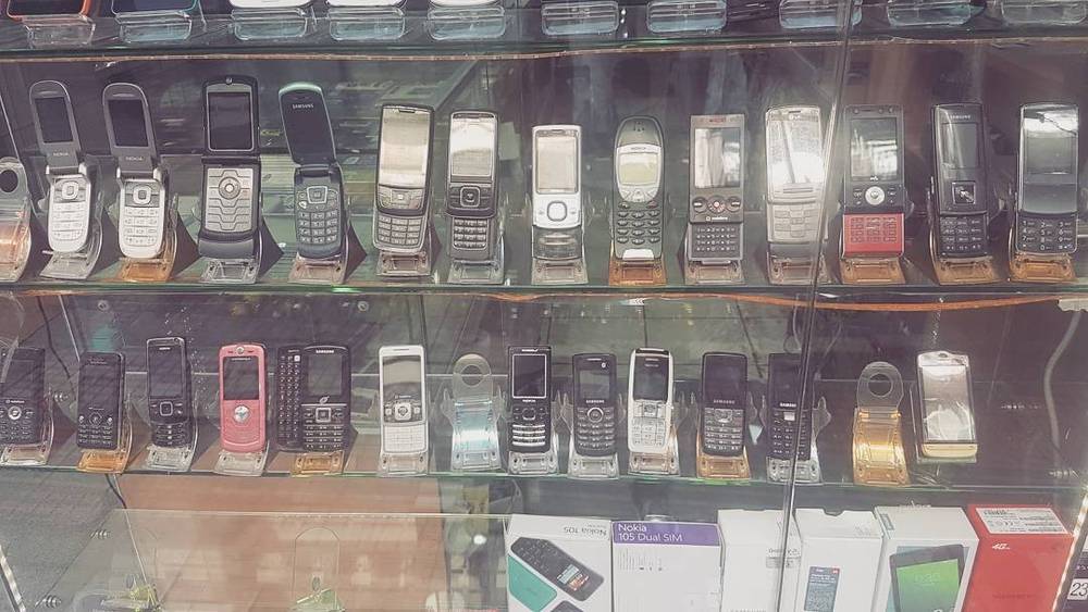 A shop display case filled with rows of old mobile phones for sale.