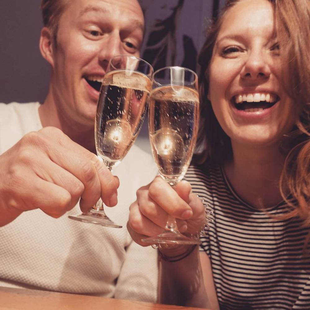 A man and woman smiling and toasting with champagne glasses.