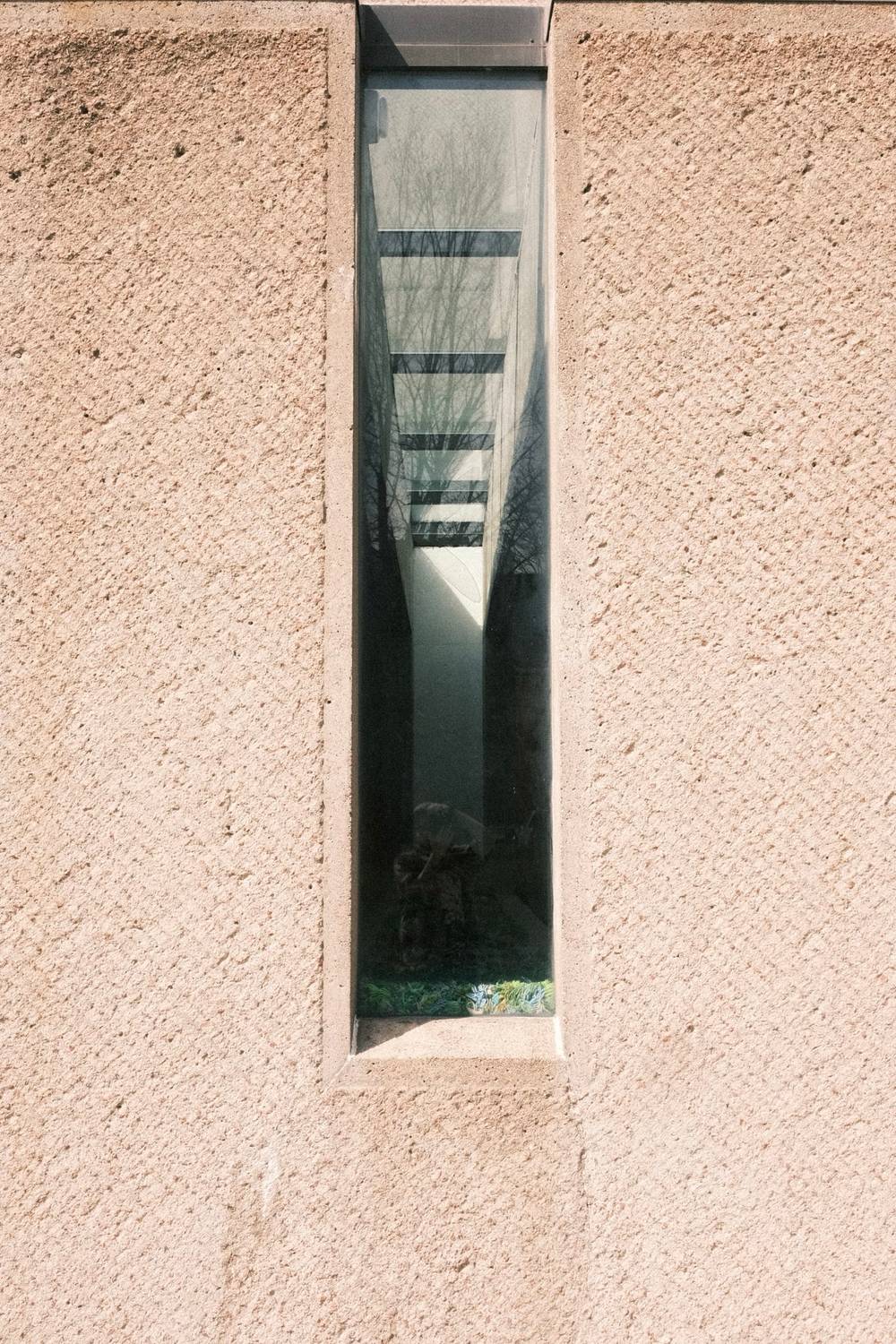 A concrete brutalist wall with a thin rectangular window