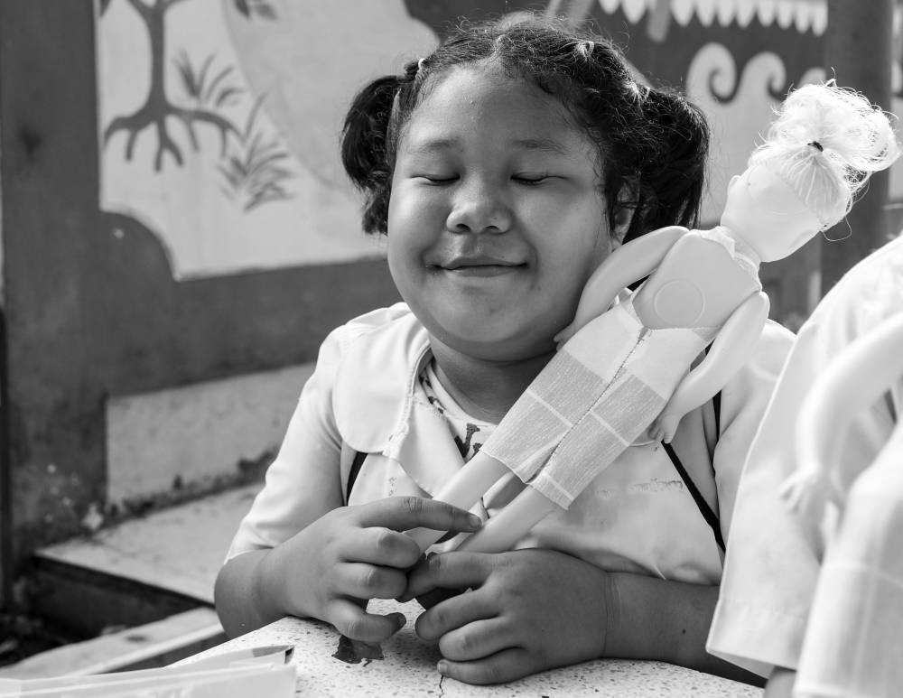 Charming Thai school child loving her Falang doll