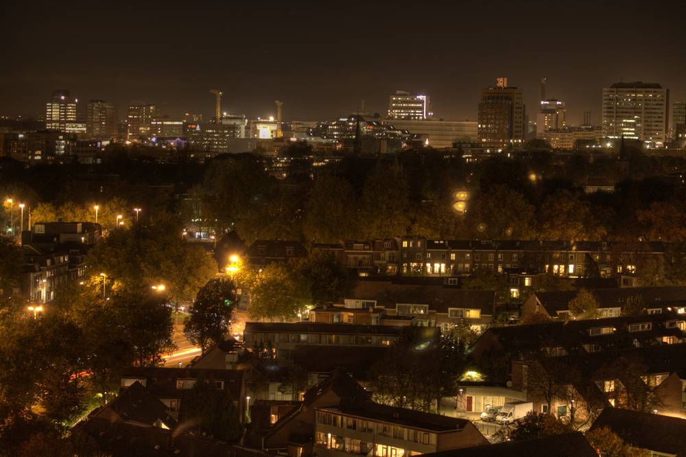 A night view over Utrecht's rooftops and streets, with city lights glowing in the distance.