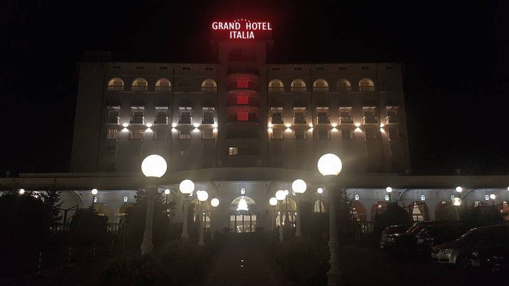 The "Grand Hotel Italia" building illuminated at night.