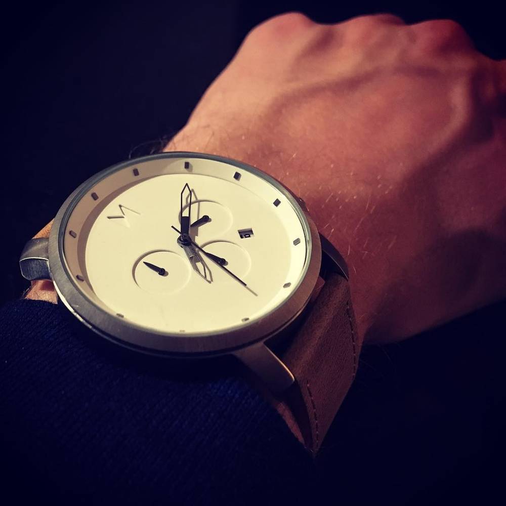 A close-up of a wristwatch with a cream-colored dial on someone's wrist.
