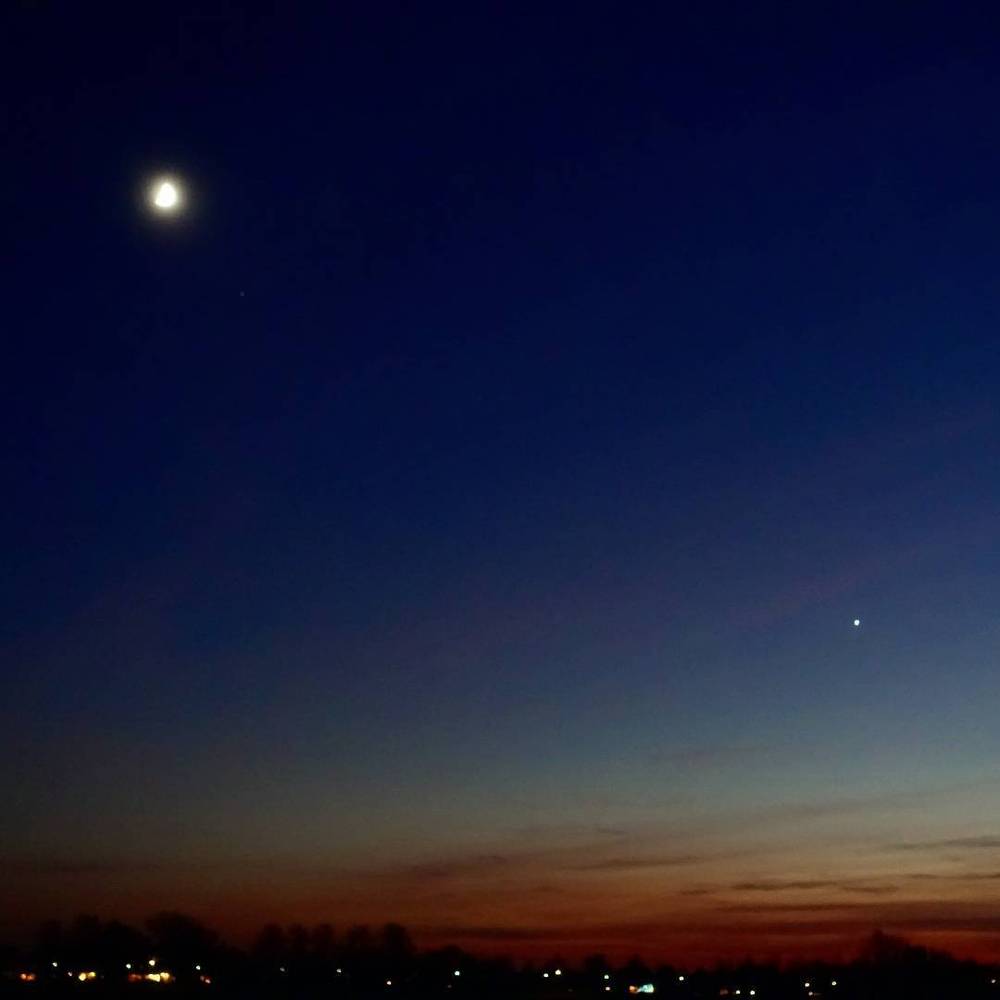The moon and two visible planets in a darkening twilight sky.