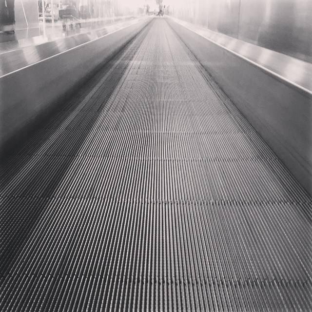 A moving walkway extending into the distance inside an airport terminal.