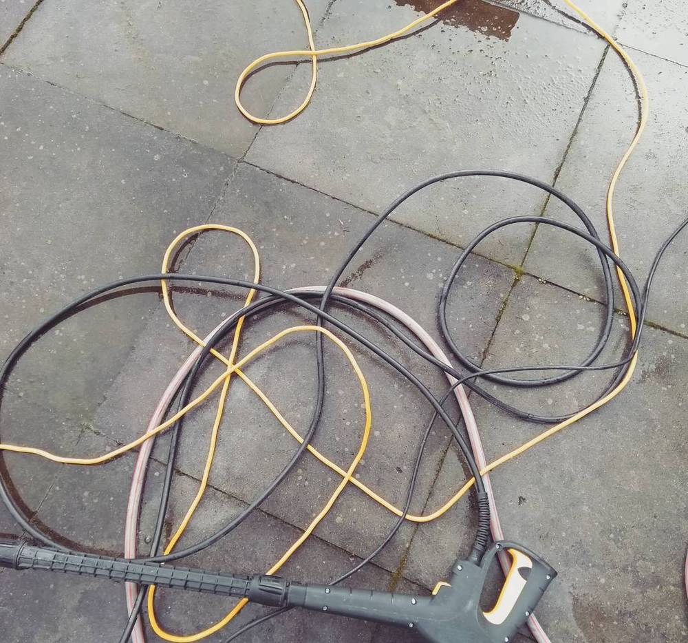 Tangled black and yellow cables coiled on a pavement.