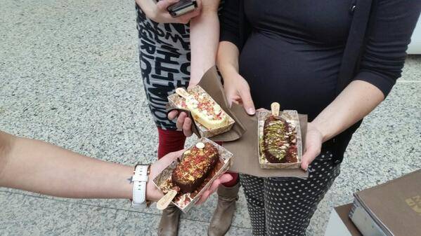 Two people hold wrapped slices of cake in their hands.