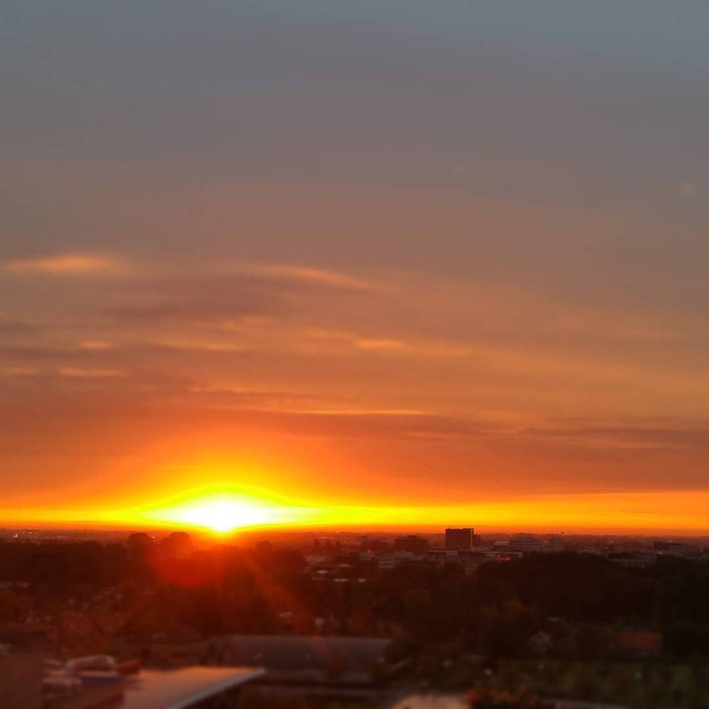 A sunset with orange and pink clouds over a city skyline.