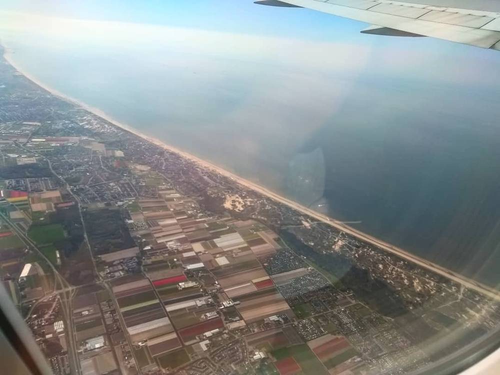 Aerial view of Dutch coastal farmland from an airplane window.