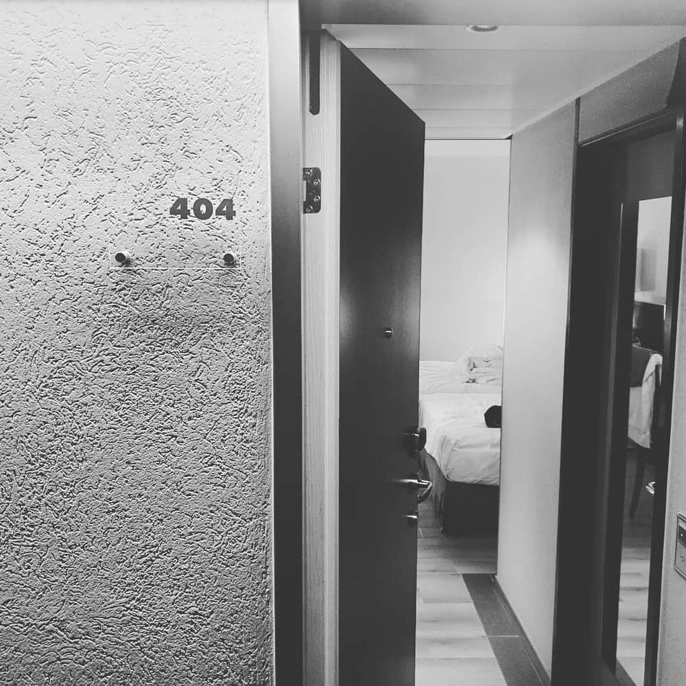 A black-and-white photo of a hotel corridor, with room number 404 on the wall beside an open door.