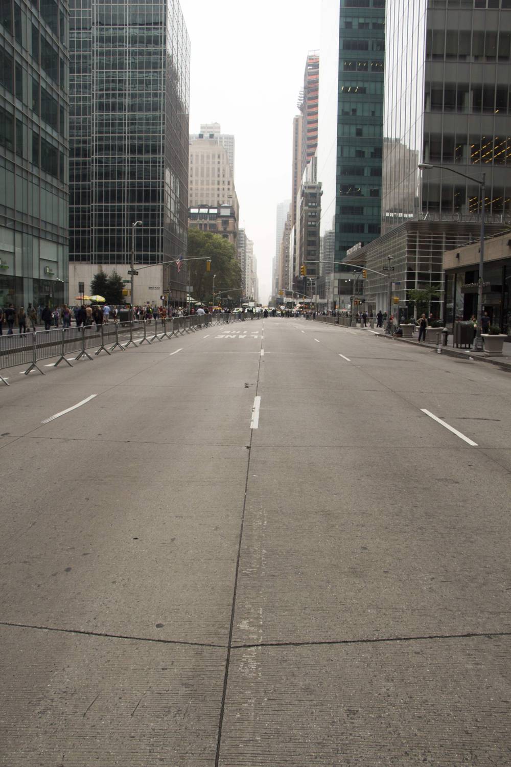 An avenue closed to traffic stretches empty between Manhattan skyscrapers during a march.