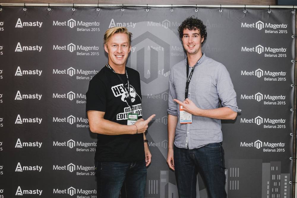 Two men pose together in front of a Meet Magento Belarus 2015 backdrop.