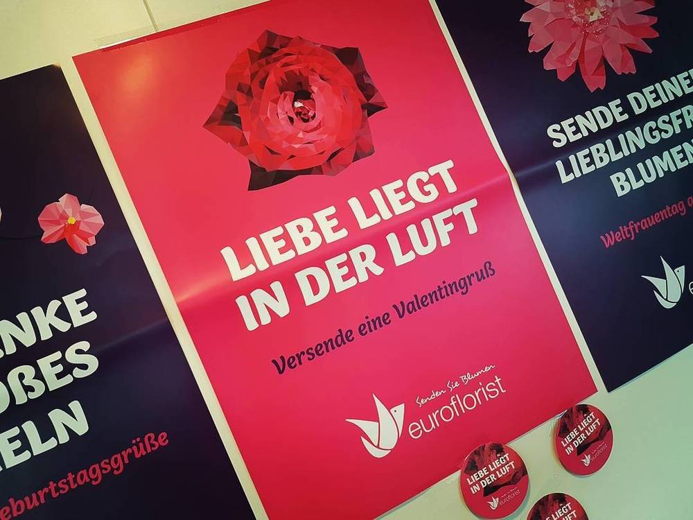 A pink Euroflorist promotional poster with German text about sending Valentine's flowers.