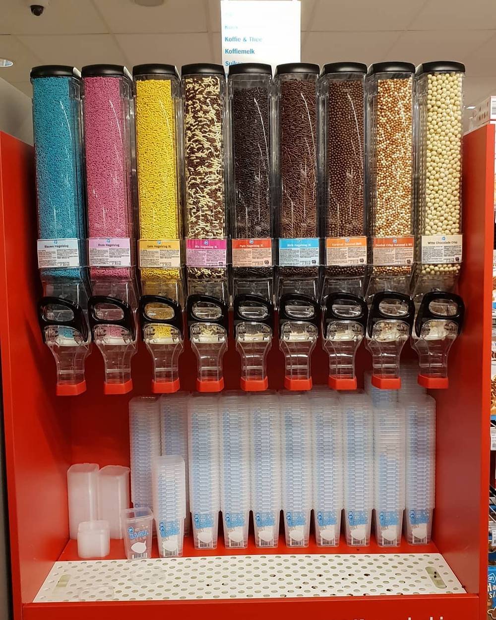 A self-serve candy dispenser wall with plastic scoop cups.