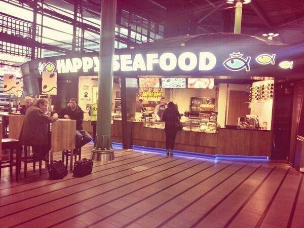 A 'Happy Seafood' restaurant stall with illuminated signage in an indoor market.