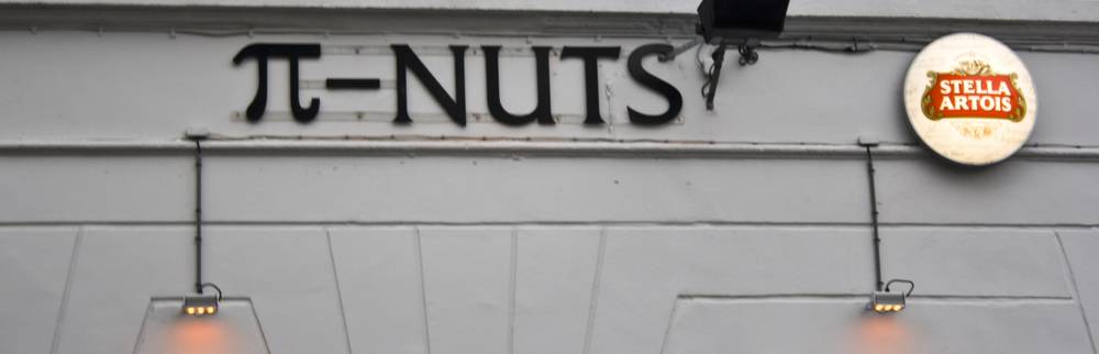 A shop sign reading 'π-NUTS' beside a Stella Artois bottle cap logo.