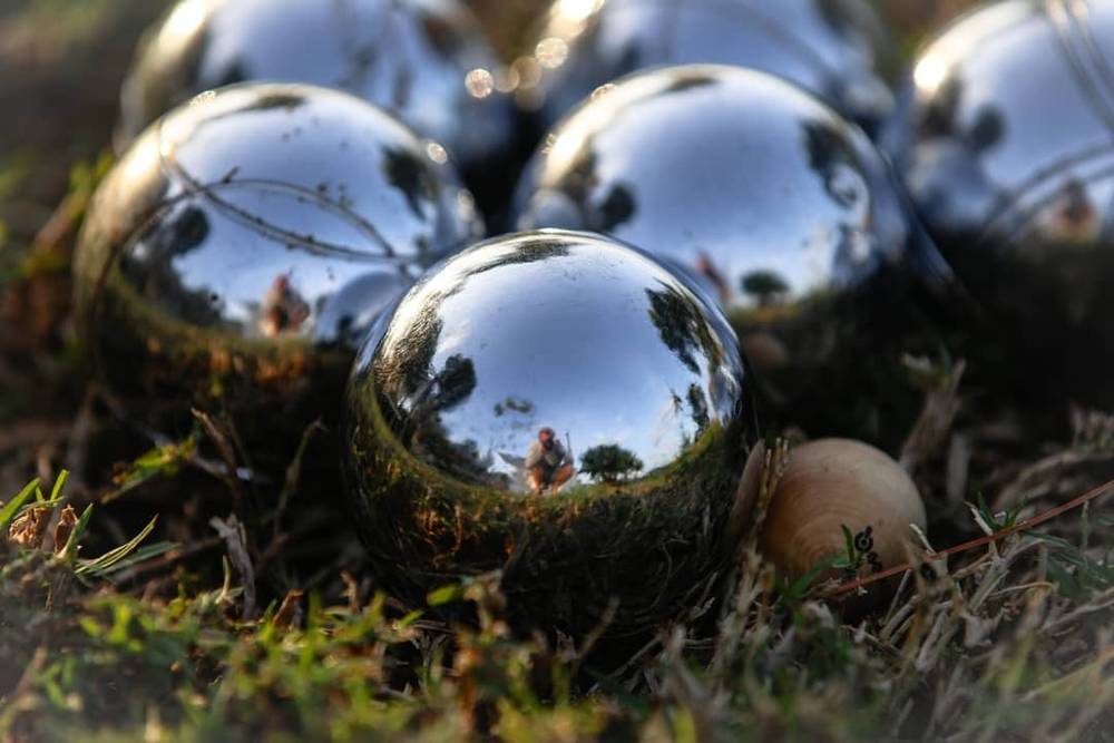 A cluster of reflective silver garden balls resting in grass.