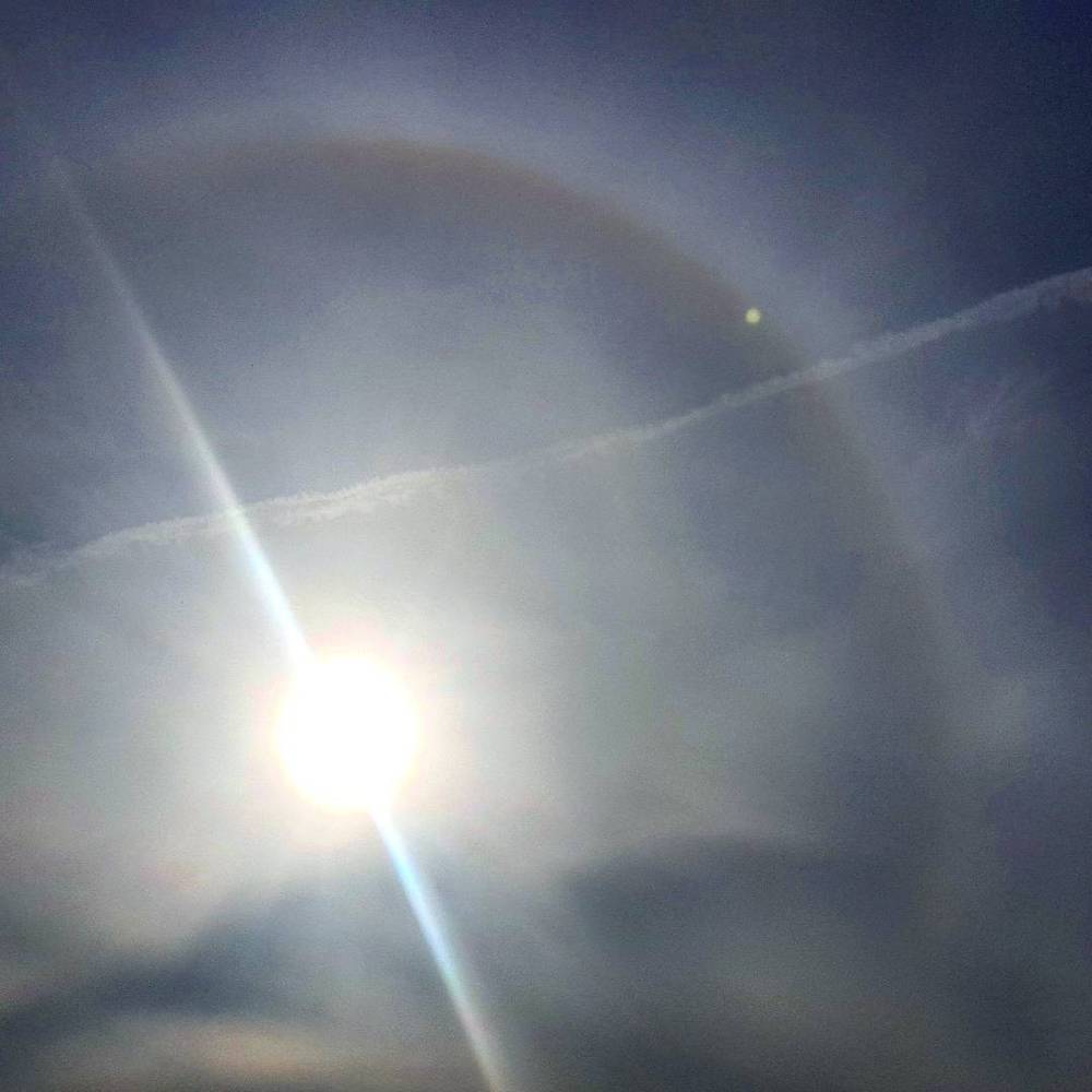A rare optical phenomenon: a halo ring around the sun in a hazy sky.