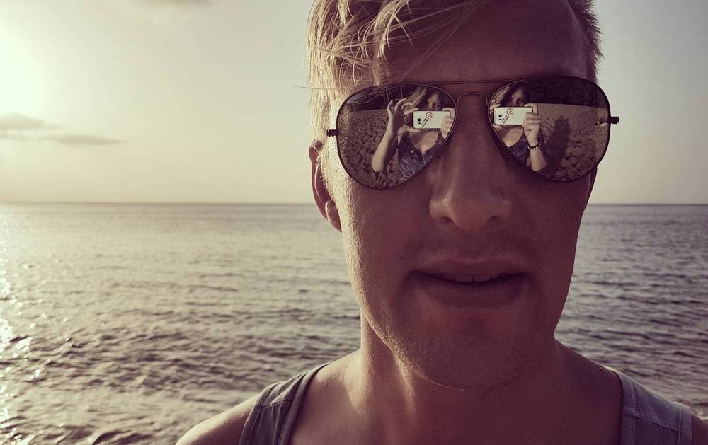 Selfie of a man in sunglasses with the sea in the background.