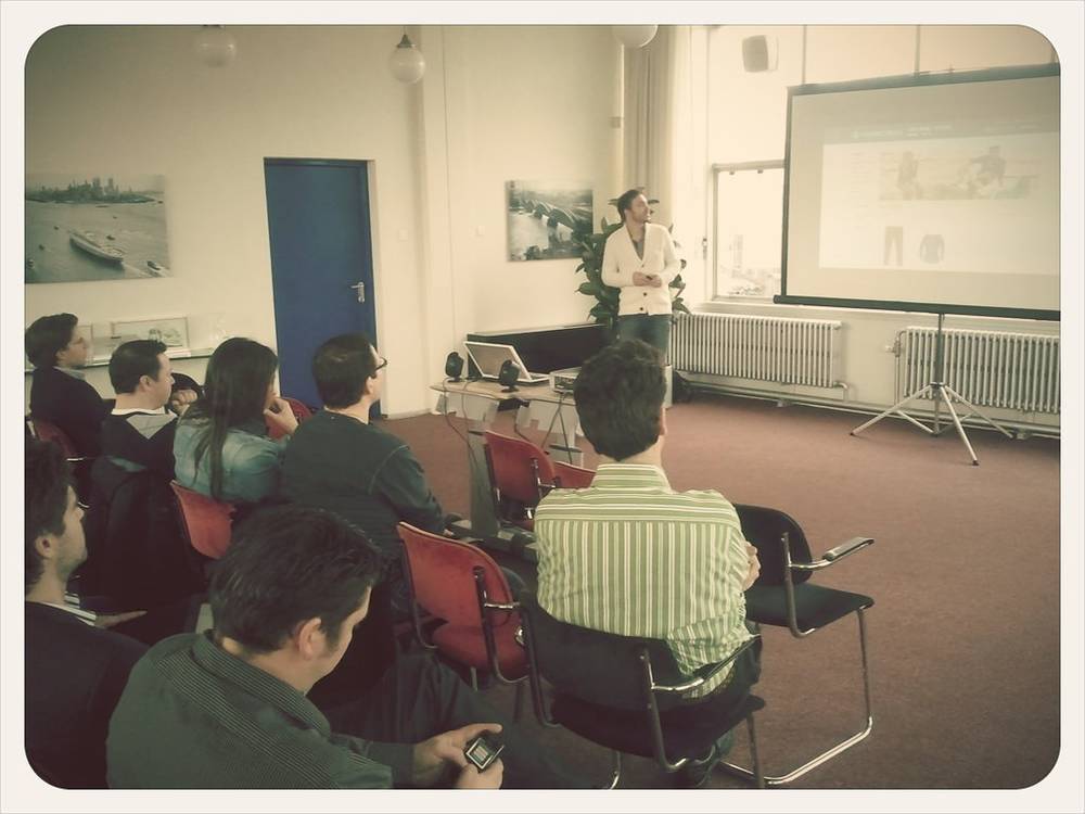 A man presents to a smaller seated group in a meeting room.