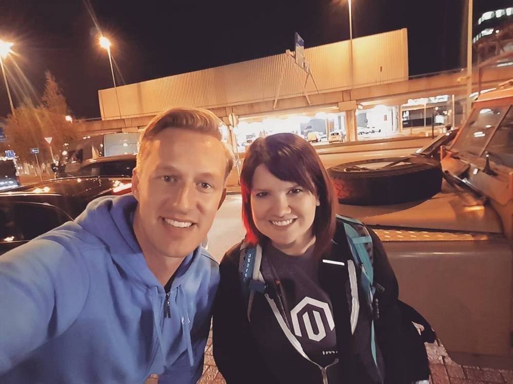 A man and woman take a nighttime selfie near a gas station.