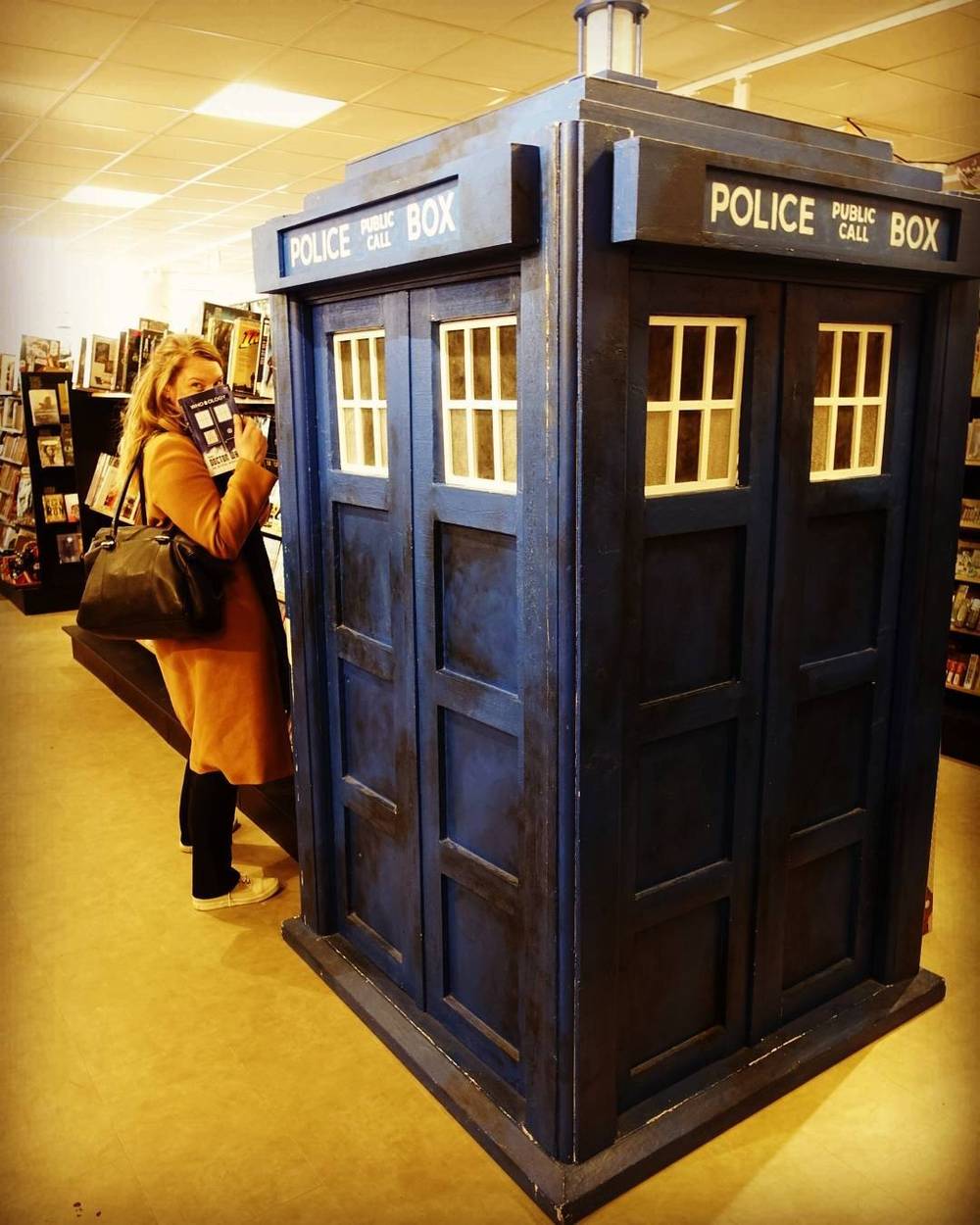 A blue police box (TARDIS) replica standing inside a bookstore.