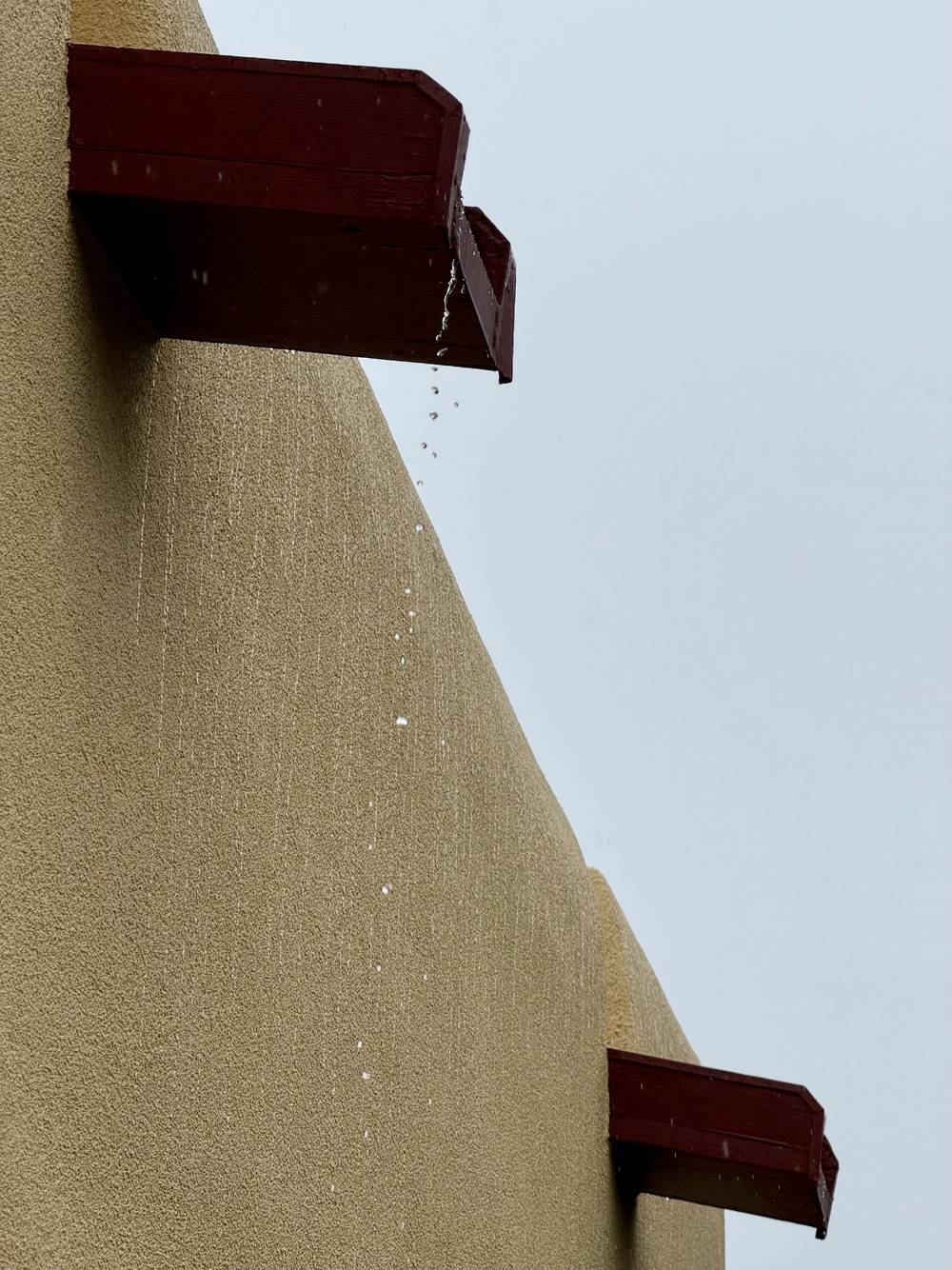 the sky is a uniform shade of gray and rain is dripping from the canales