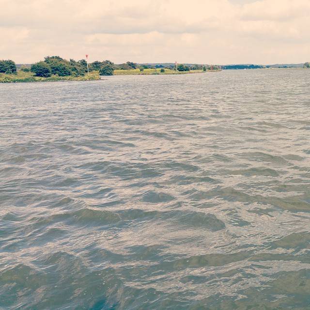 Calm water stretching to the horizon under an overcast sky.