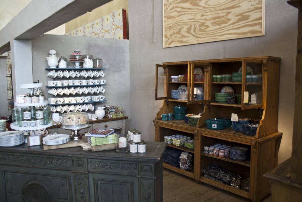 A rustic wooden cabinet displays stacked dishware and ceramics in a home goods shop.