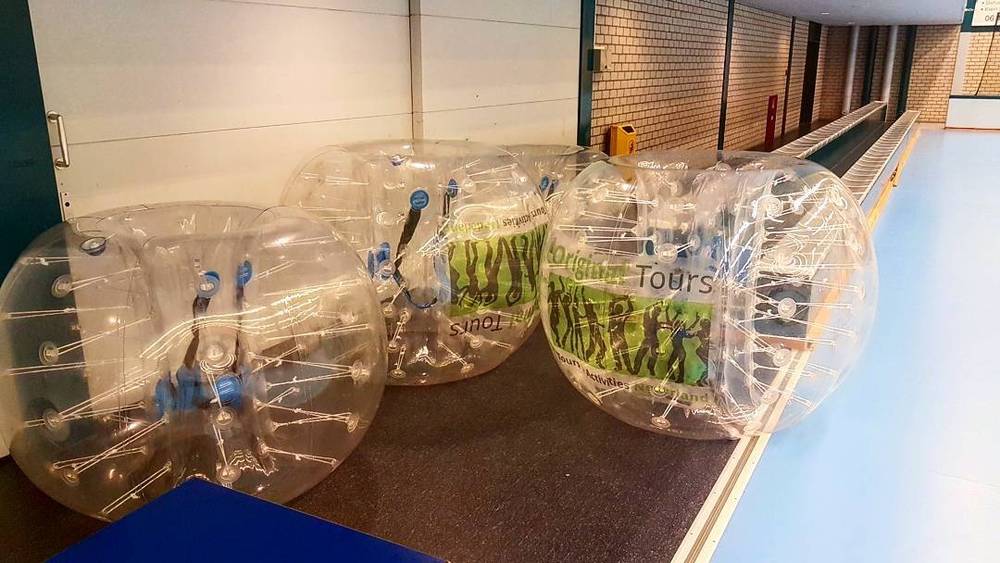 Inflatable bubble-soccer suits lined up in a gym corridor for a team event.