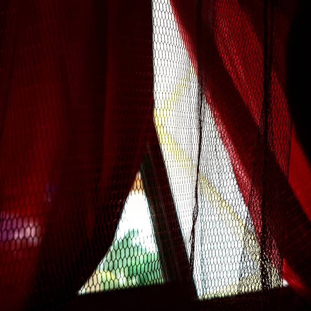 Close-up of red mosquito netting curtains lit from behind.