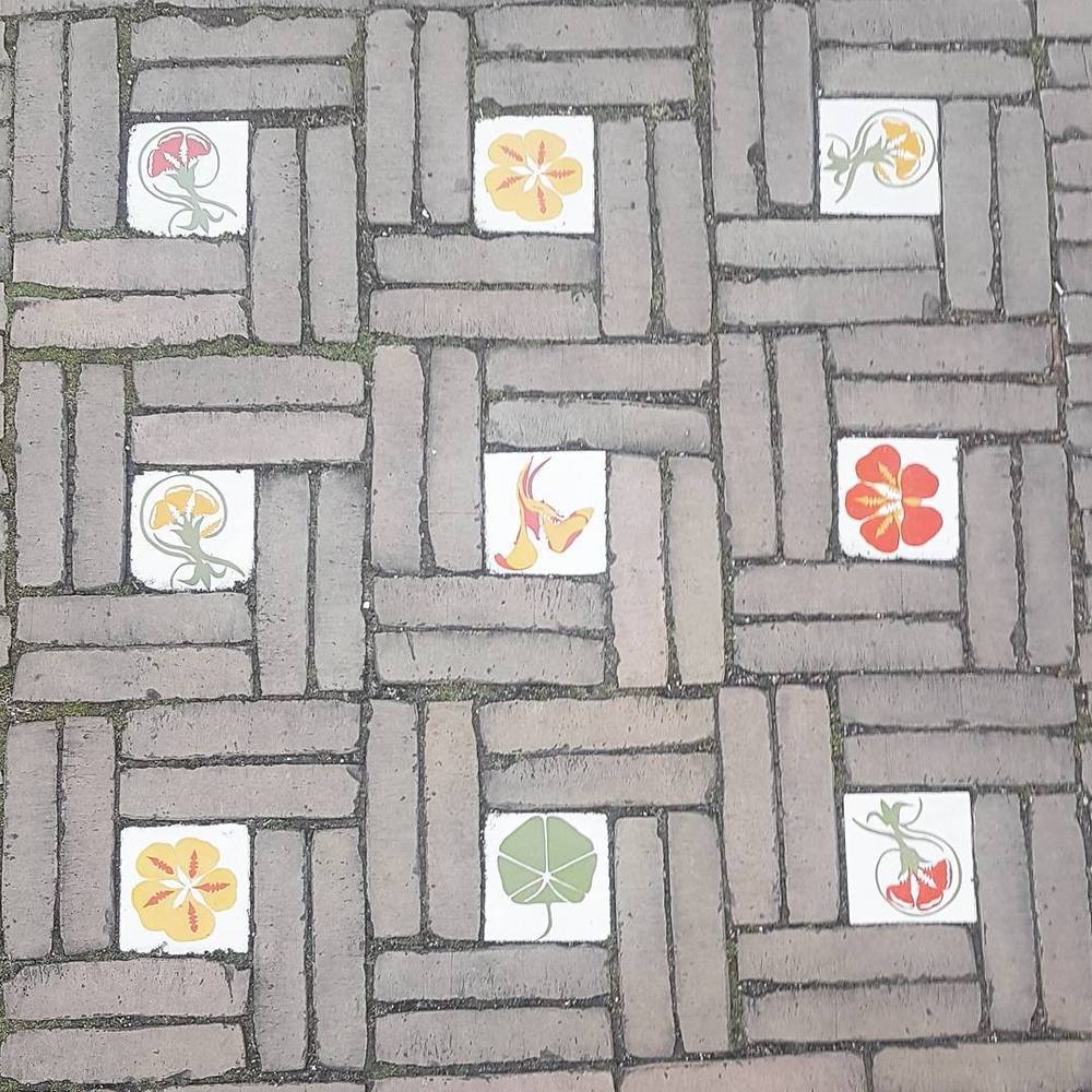Decorative floral tiles set into a brick-paved street.
