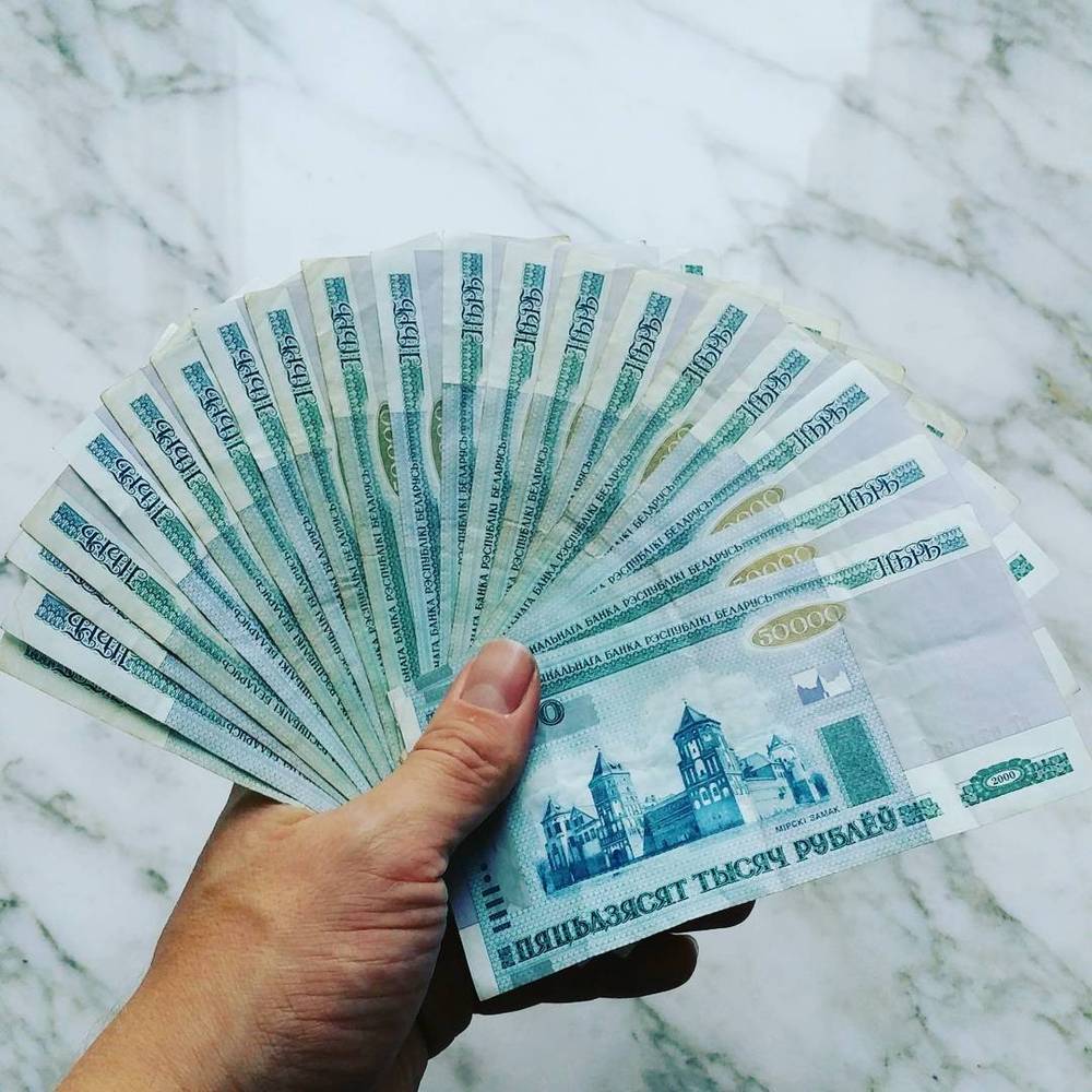 A hand fanning out a stack of Belarusian ruble banknotes.