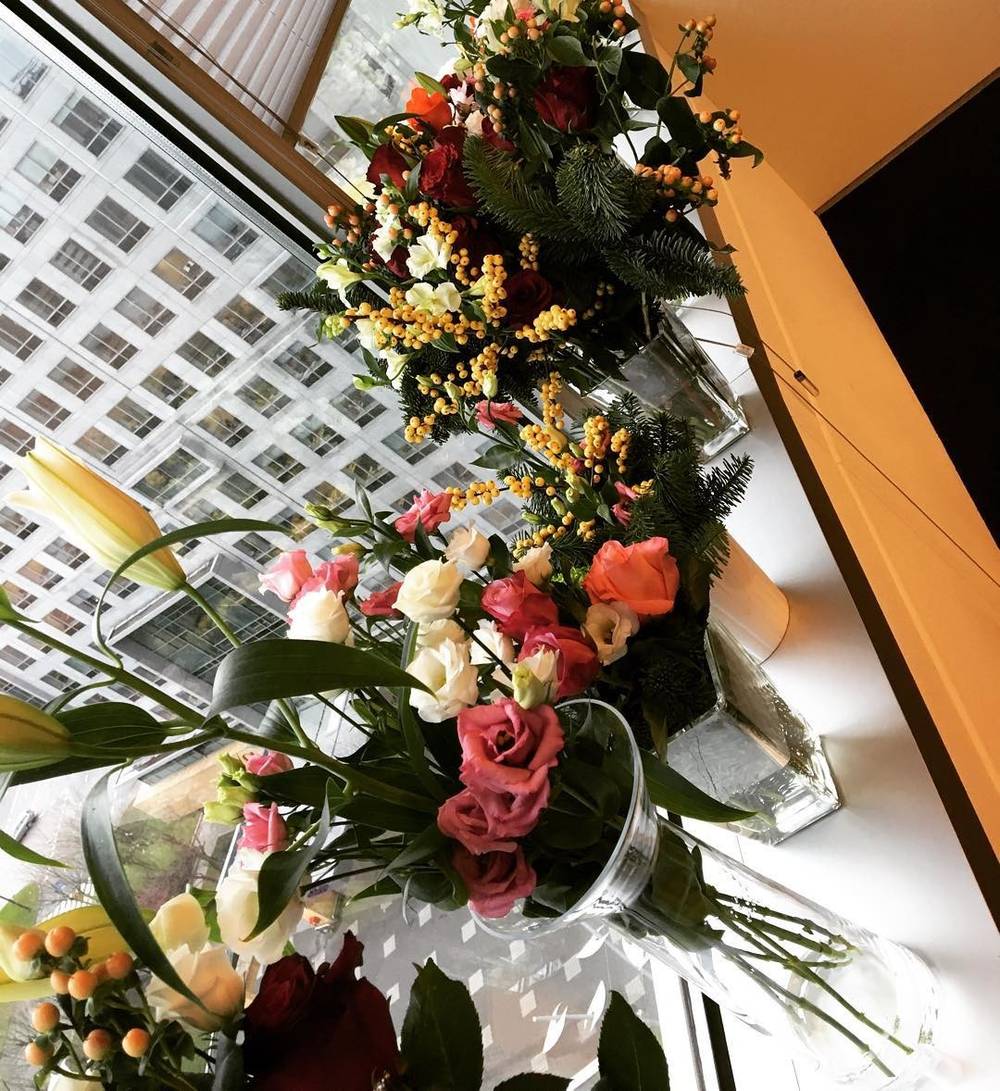 Bouquets of flowers on a windowsill overlooking a city skyline.