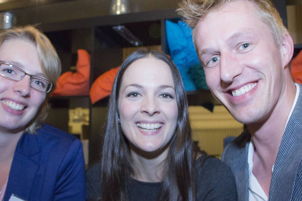 Two women and a man smile together for a photo at the networking event.