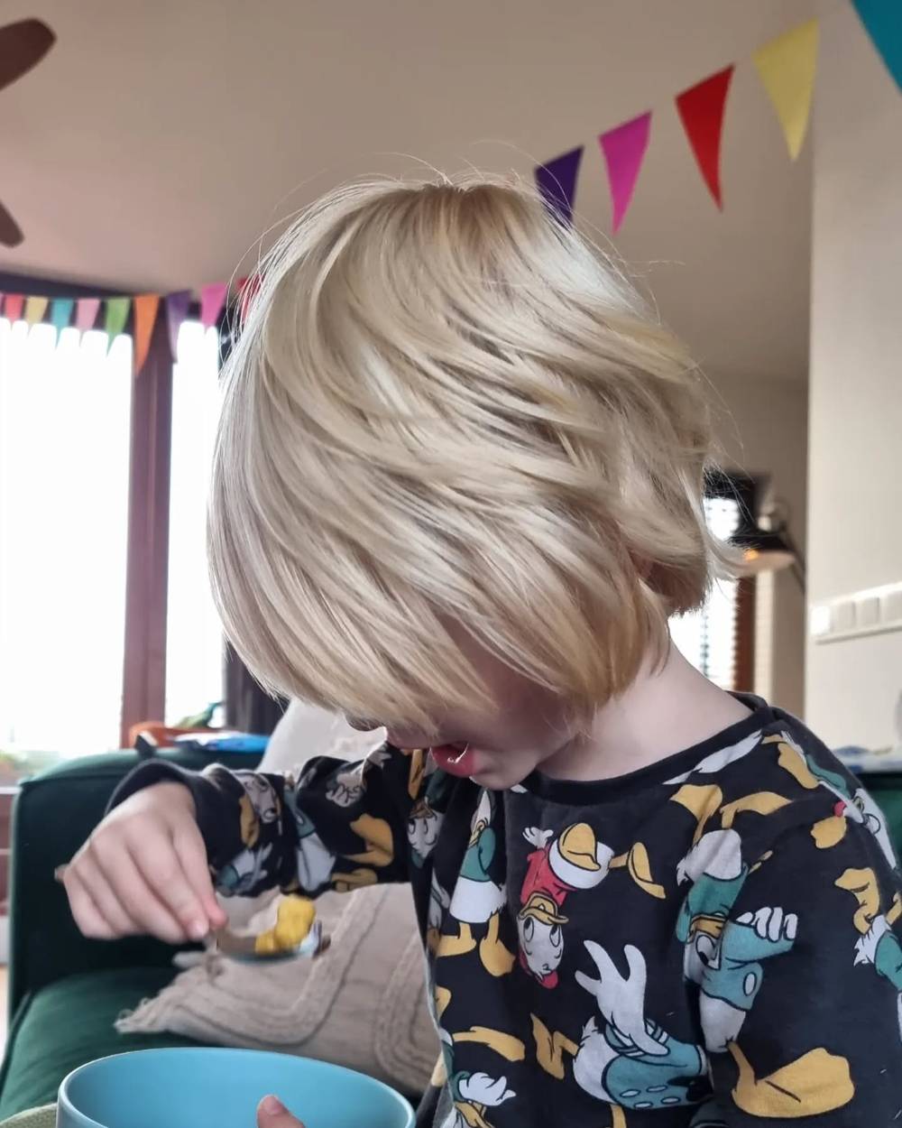 A child eating breakfast at a table decorated with colorful bunting, wearing a patterned pajama shirt.