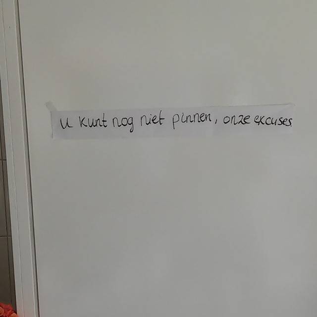 A handwritten sign taped to a wall reading 'U kunt nog niet pinnen, onze excuses' (card payment not yet possible, our apologies).