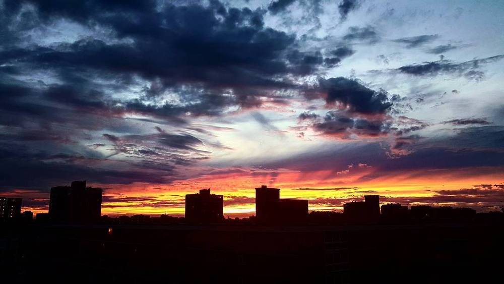 Dramatic clouds over a city skyline at sunset.
