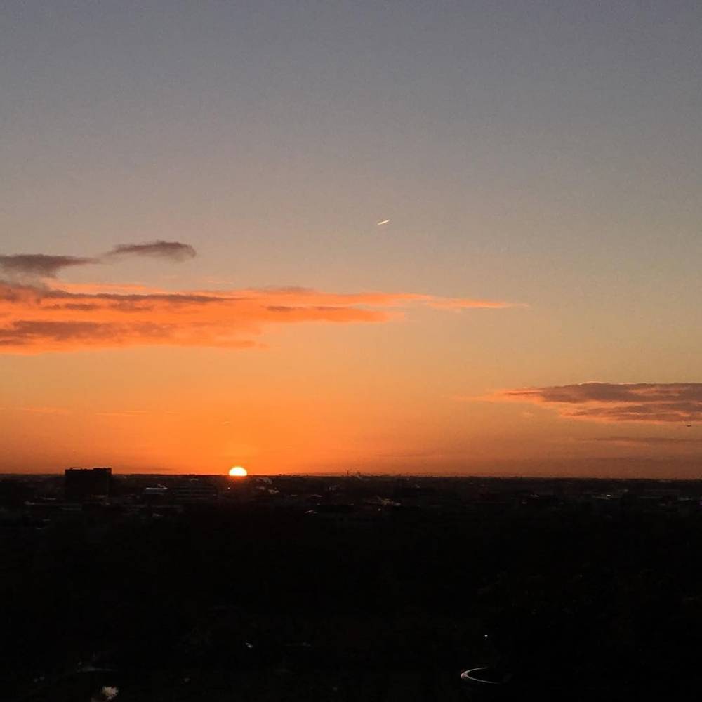 A dark orange sunset glow along the horizon under a mostly clear sky.