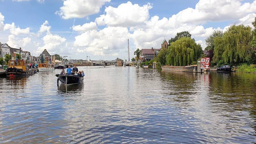 A river view with a small passenger boat and a bridge in the distance.