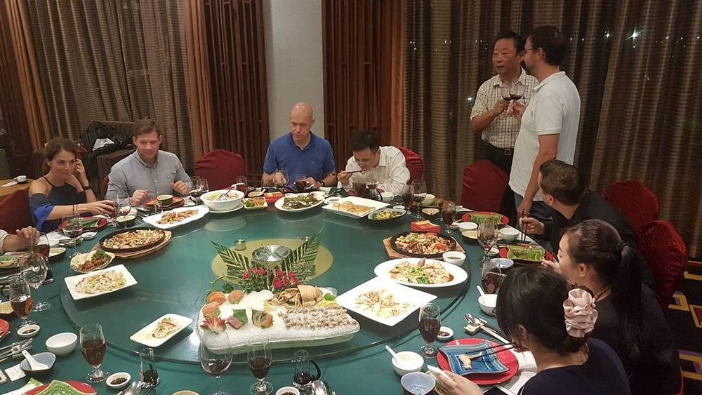 A group having dinner around a round table in a private restaurant room, with dishes spread across a lazy Susan.