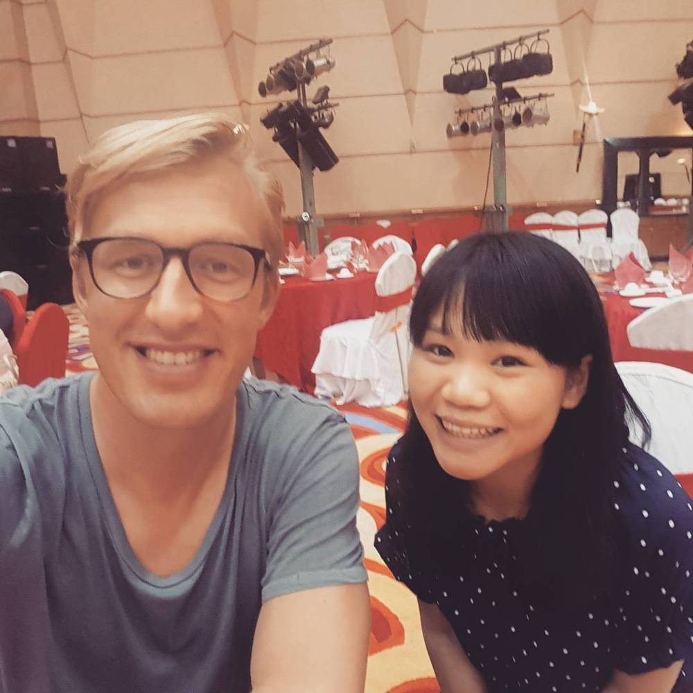 Selfie with his conference translator at a banquet table, both smiling.