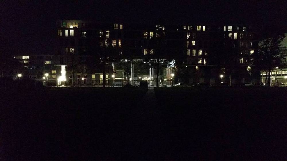 Apartment buildings lit up at night along a waterfront.
