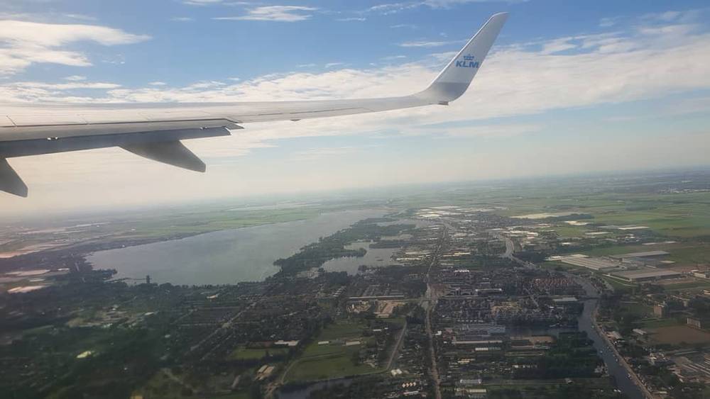 Aerial view of farmland and a river from an airplane window, wing visible.