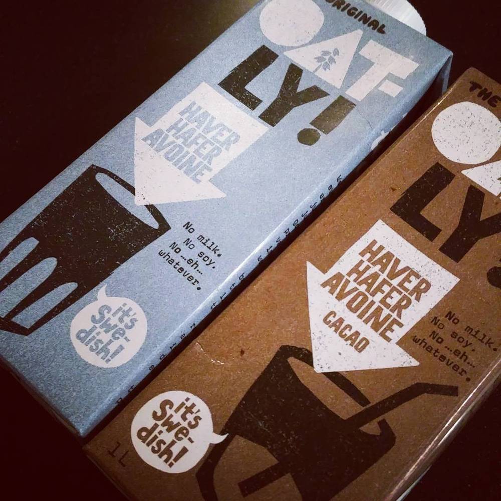 Two boxes of Swedish oat drink cartons labeled "Oatly" on a table.