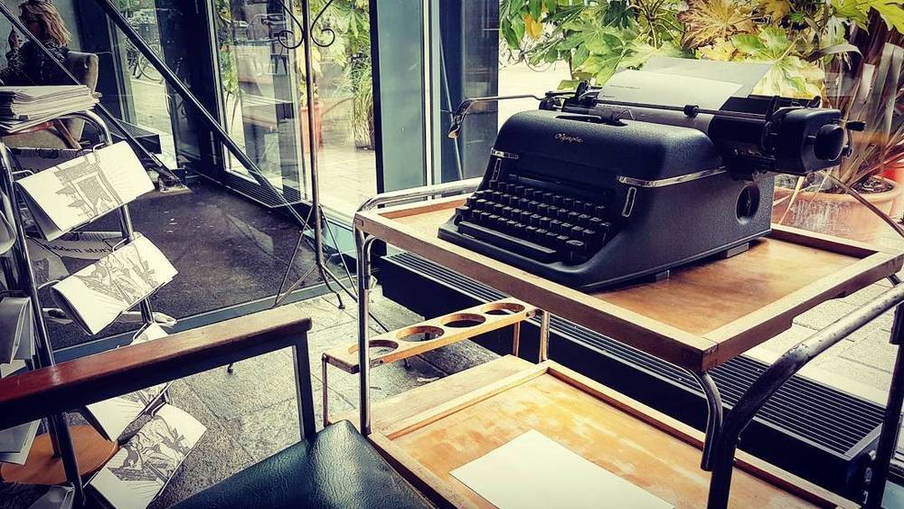 A vintage typewriter displayed on a small table near a window.